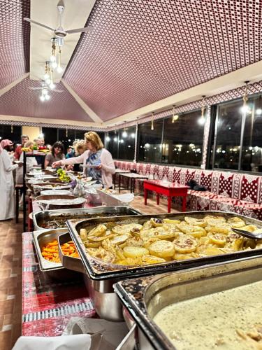 - un buffet avec des personnes préparant des repas dans un restaurant dans l'établissement Feras Camp Wadi Rum, à Wadi Rum
