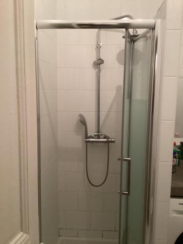 une douche avec une porte vitrée dans une salle de bain dans l'établissement Chambre chez le habitant 282 rue Lecourbe 75015, à Paris