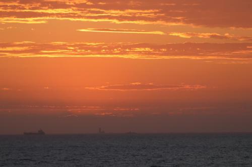 an orange sunset over the ocean with ships at Dolphin Beach Self Catering Unit in Walvis Bay