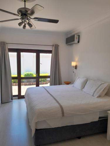 a bedroom with a bed with a ceiling fan at Almost Heaven in Durban