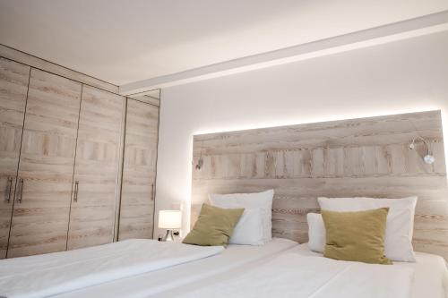 a bedroom with a white bed with a wooden headboard at Hotel Antoniushof in Ruhstorf