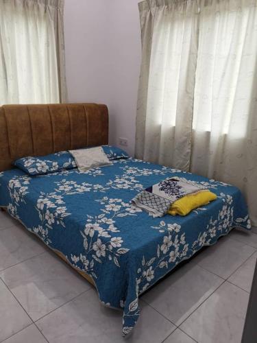 Bett mit blauer Bettdecke und gelben Kissen in der Unterkunft Homestay Bajet Cikyah in Kepala Batas