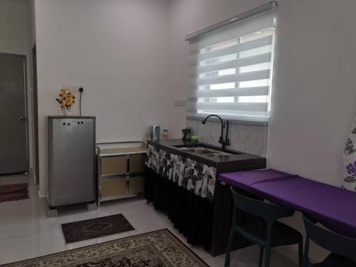 uma cozinha com um lavatório e uma bancada roxa em Homestay Bajet Cikyah em Kepala Batas