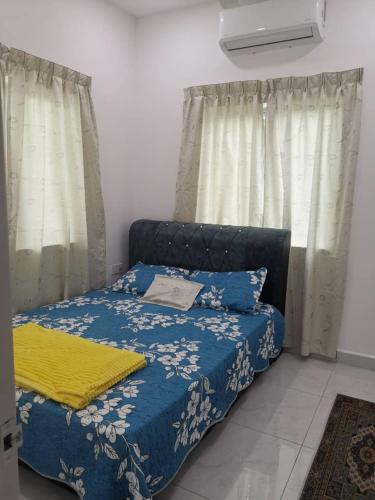 a bedroom with a bed with a blue blanket and curtains at Homestay Bajet Cikyah in Kepala Batas