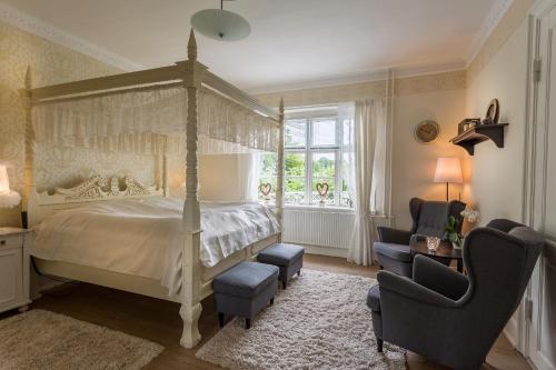 a bedroom with a canopy bed and a chair at Jungshoved Præstegård B&B in Præstø