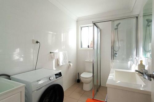 ein weißes Bad mit einem WC und einer Dusche in der Unterkunft New and Cozy 2 Bedrooms Granny Flat with Aircon & Pool in Baulkham Hills