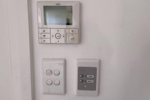 an electronic device on a wall with two controllers at New and Cozy 2 Bedrooms Granny Flat with Aircon & Pool in Baulkham Hills