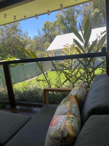 a couch on a balcony with a view of a yard at OAK FLATS - Cosy Getaway in Lake Illawarra