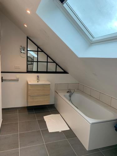 een badkamer met een bad en een wastafel bij Loft au calme, idéal pour famille, proche de Reims in Saint-Brice-et-Courcelles