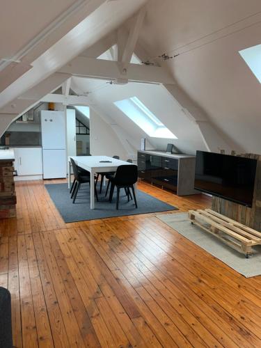 - un salon mansardé avec une table et une télévision dans l'établissement Loft au calme, idéal pour famille, proche de Reims, à Saint-Brice-Courcelles