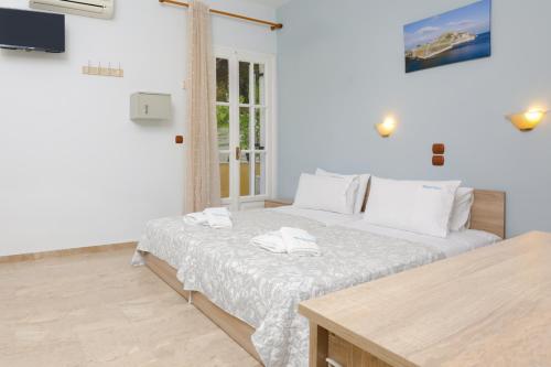 a white bedroom with a bed with two towels on it at Marina Apartments, Agios Gordios Corfu in Agios Gordios