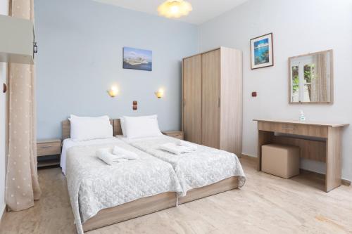 a white bedroom with a bed and a desk at Marina Apartments, Agios Gordios Corfu in Agios Gordios