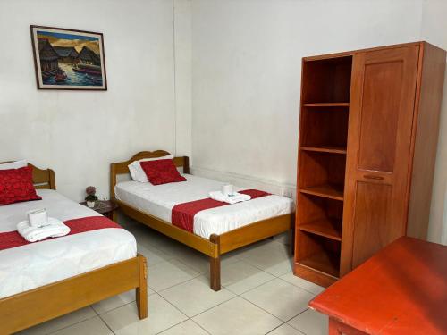 a bedroom with two beds and a book shelf at Hospedaje Casa Amazónica Iquitos in Iquitos