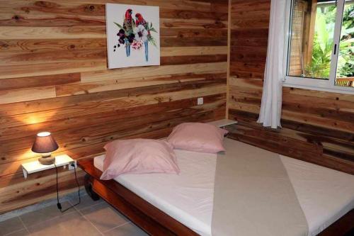 a bedroom with wooden walls and a bed with two pillows at CHALET DE LISE in Bras-Panon