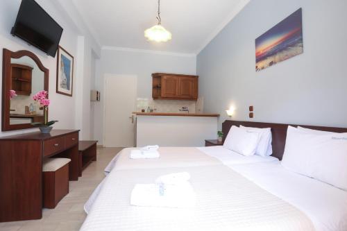 a bedroom with a large white bed with two towels at Marina Apartments, Agios Gordios Corfu in Agios Gordios