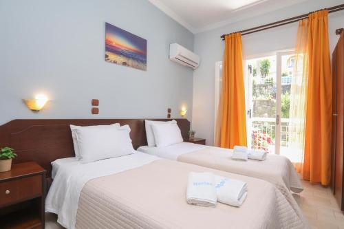 two beds in a room with orange curtains at Marina Apartments, Agios Gordios Corfu in Agios Gordios