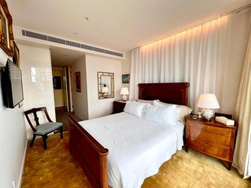 a bedroom with a bed and a chair and a television at Sydney Cosmopolitan CBD Apartment in Sydney