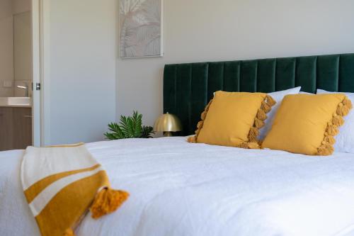 a white bed with yellow pillows and a green headboard at Homely Entire house in Clyde in Clyde