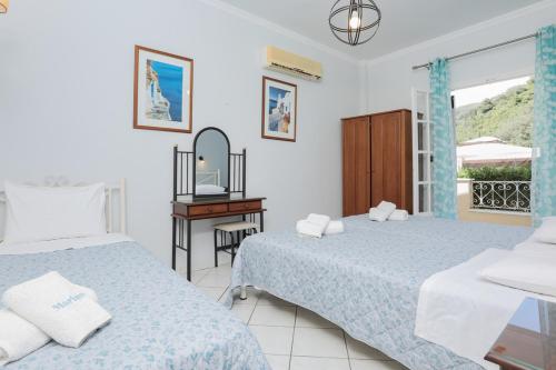 a bedroom with two beds and a mirror at Marina Apartments, Agios Gordios Corfu in Agios Gordios