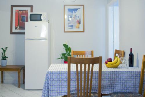 a kitchen with a table with a white refrigerator at Marina Apartments, Agios Gordios Corfu in Agios Gordios