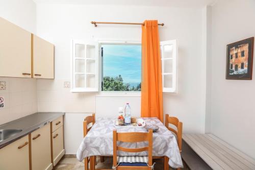 a small kitchen with a table and a window at Marina Apartments, Agios Gordios Corfu in Agios Gordios