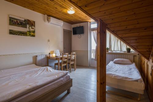 a bedroom with two beds and a table in it at Dobosi Pincészet in Szentantalfa