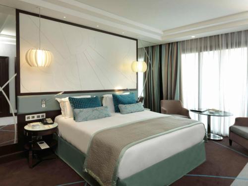 a hotel room with a large bed and a large screen at Sofitel Beirut Le Gabriel in Beirut