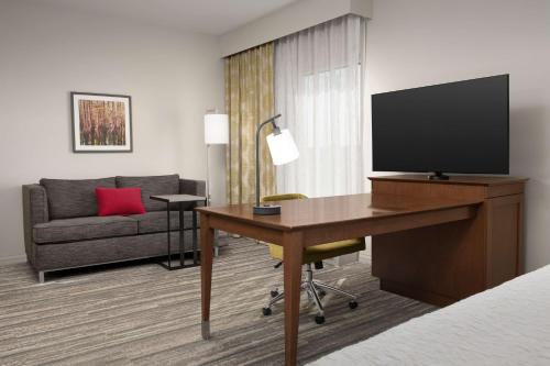 a hotel room with a desk with a television and a couch at Hampton Inn & Suites Orangeburg, SC in Orangeburg