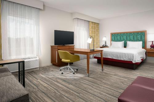 a hotel room with a bed and a desk with a television at Hampton Inn & Suites Orangeburg, SC in Orangeburg