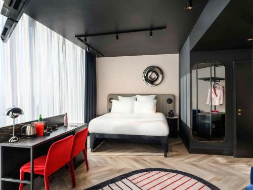 a bedroom with a bed and a desk with red chairs at TRIBE Budapest Stadium in Budapest