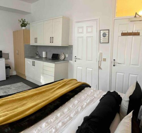 a bedroom with a bed and a kitchen with white cabinets at Streatham Studio in London