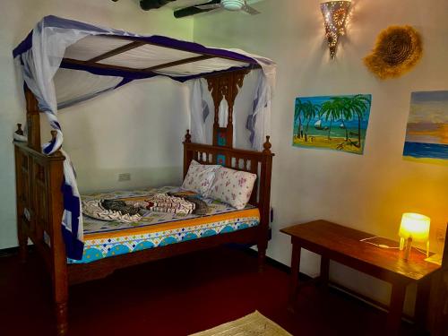 1 dormitorio con cama con dosel y mesa en Milele Lodge, en Michamvi