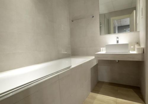 a white bathroom with a sink and a bath tub at 1min walk studio in front of JBR beach in Dubai