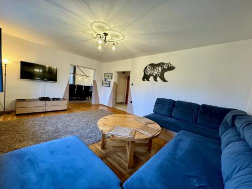 a living room with a blue couch and a table at Domek Monte Black z jacuzzi i sauną fińską in Stronie Śląskie