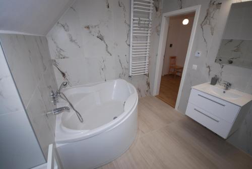 a white bathroom with a tub and a sink at Pęglity jezioro in Gietrzwałd