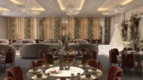 a dining room with tables and a wedding dress on the wall at Enala Hotel- Umluj in Umm Lujj