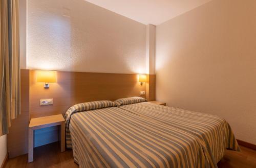 a hotel room with a bed and a table and lights at Almirall Apartaments in Lloret de Mar