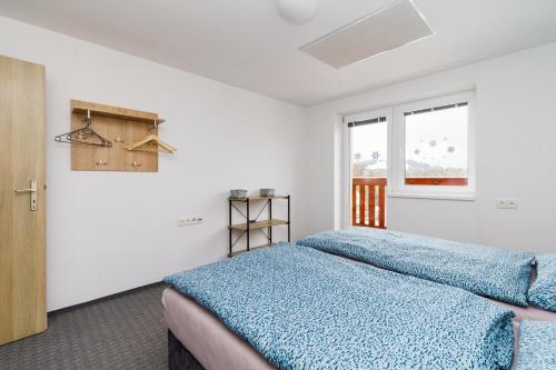 a bedroom with a blue bed and a window at APARTMÁN Abertamská Chata in Abertamy