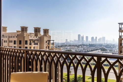 a chair on a balcony with a view of a city at Chic 2 Beds With Pool View Asayel B3 MJL in Dubai
