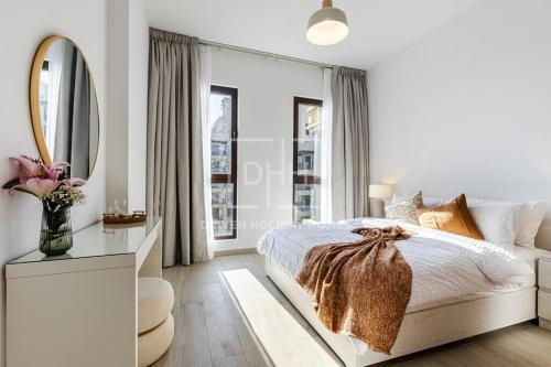 een witte slaapkamer met een bed en een spiegel bij Chic 2 Beds With Pool View Asayel B3 MJL in Dubai