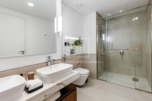 a bathroom with two sinks and a glass shower at Chic 2 Beds With Pool View Asayel B3 MJL in Dubai