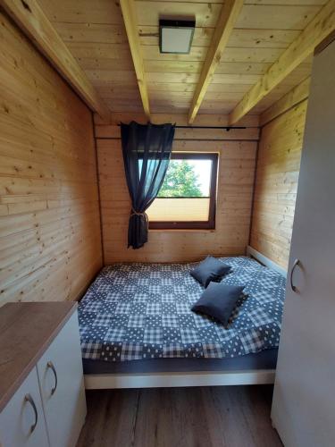 Łóżko w drewnianym pokoju z oknem w obiekcie Rodzinna Przystań w mieście Jarosławiec