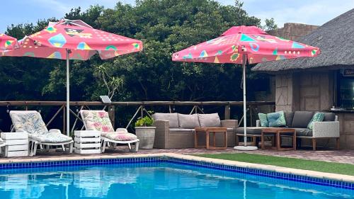 two umbrellas and chairs next to a swimming pool at Sunbonani Lodge in Maputo