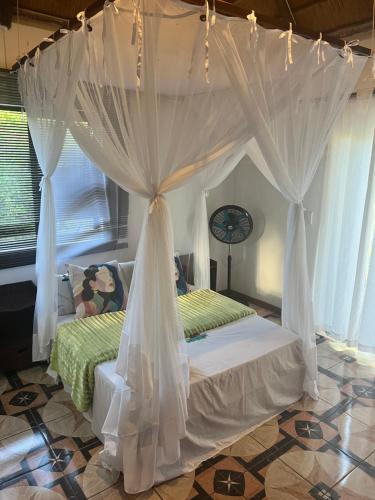 a bedroom with a canopy bed with white curtains at Sunbonani Lodge in Maputo