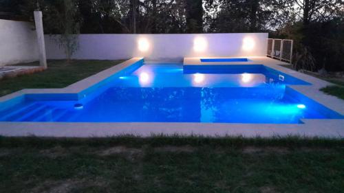 a swimming pool with lights in a backyard at night at Acacias Mina Clavero in Mina Clavero