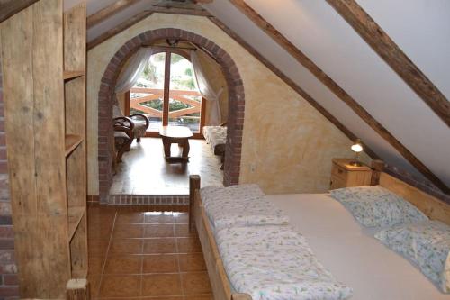 an attic bedroom with a bed and an arched window at Chalupa Střítež in Vělopolí