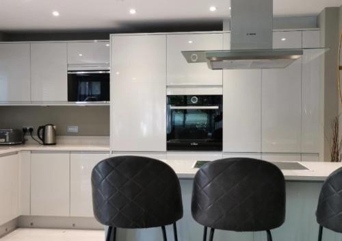 a kitchen with white cabinets and black stools at 2 Bedroom Apartment, Free Parking in York