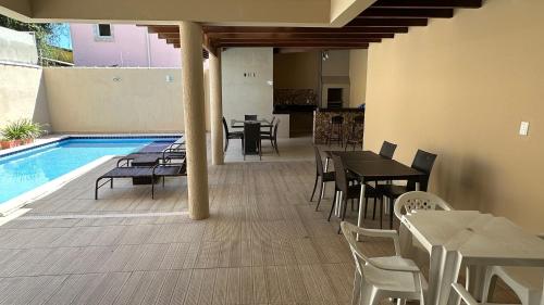 a patio with tables and chairs next to a swimming pool at Recanto Ville House in Porto Seguro