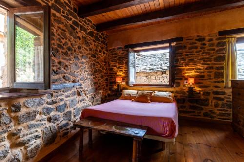a bedroom with a bed in a stone wall at Casa de turismo rural Sardom3 in Bembibre