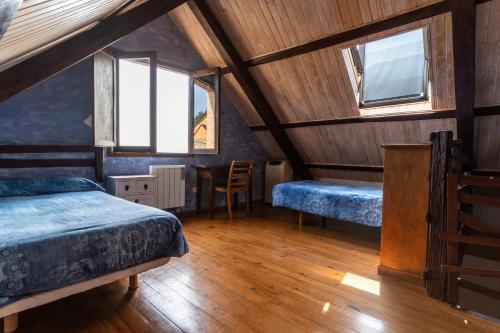 a attic room with two beds and a table at Casa de turismo rural Sardom3 in Bembibre